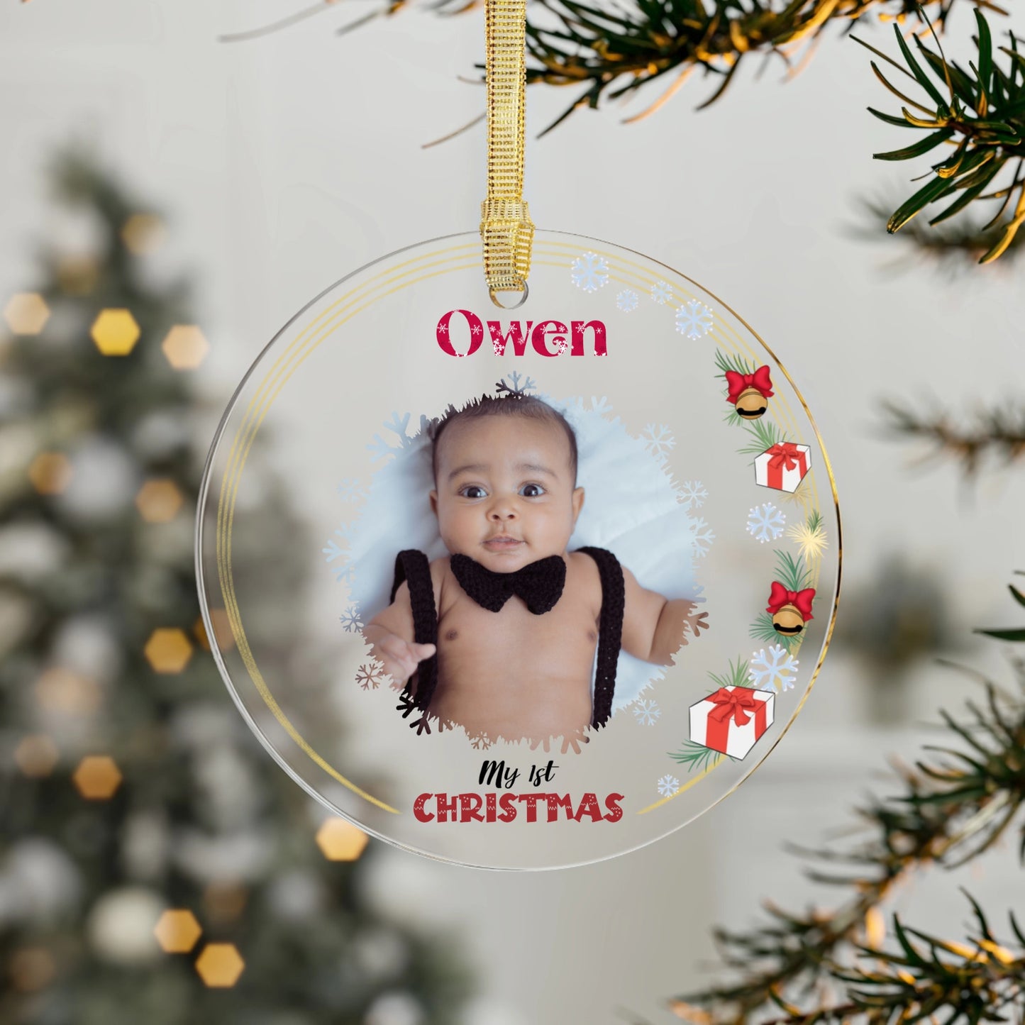 Personalized Christmas ornament with a baby's photo and festive design, hanging against a blurred Christmas tree background.